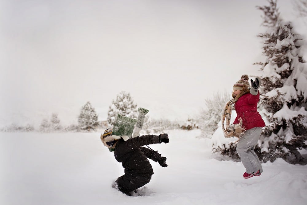 children jumping into piles of snow