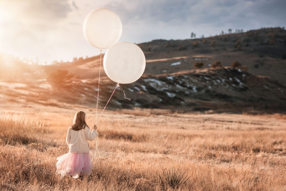 girl playing with balloons in a field