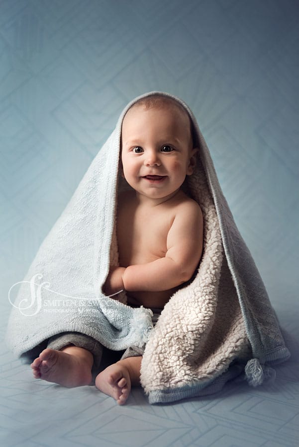 smiling baby boy sitting up with a blue blanket {boulder baby photographer}