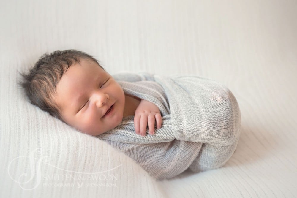 newborn baby smiling and sleeping wrapped in gray {boulder newborn photographer}