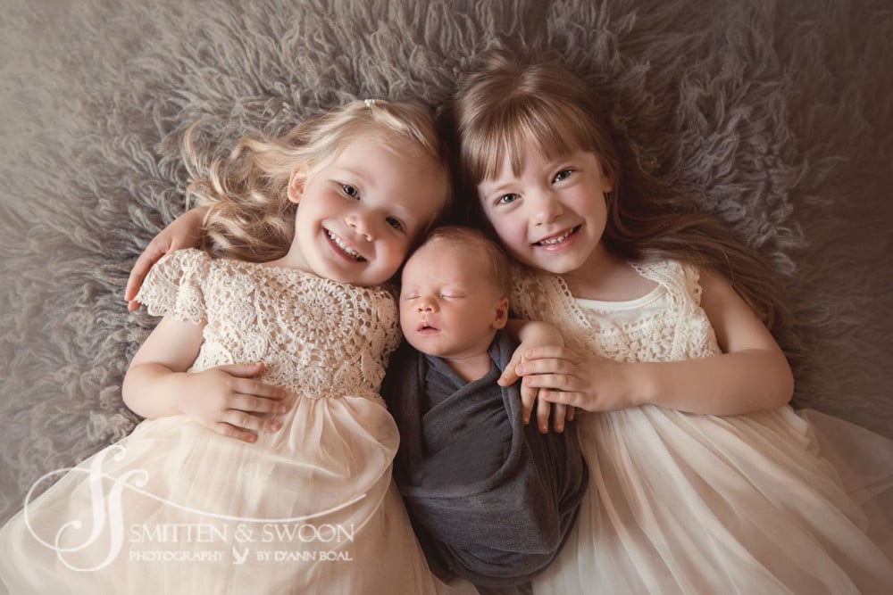 big sisters holding their newborn brother smiling {boulder newborn photographer}