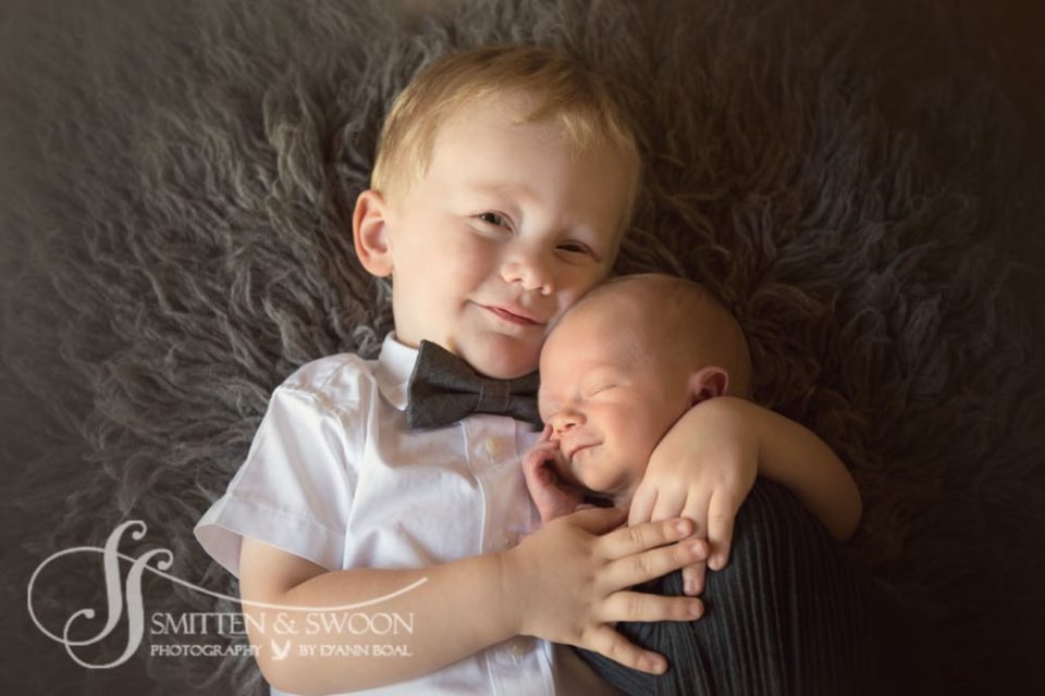 brother holding newborn baby smiling {boulder newborn photographer}