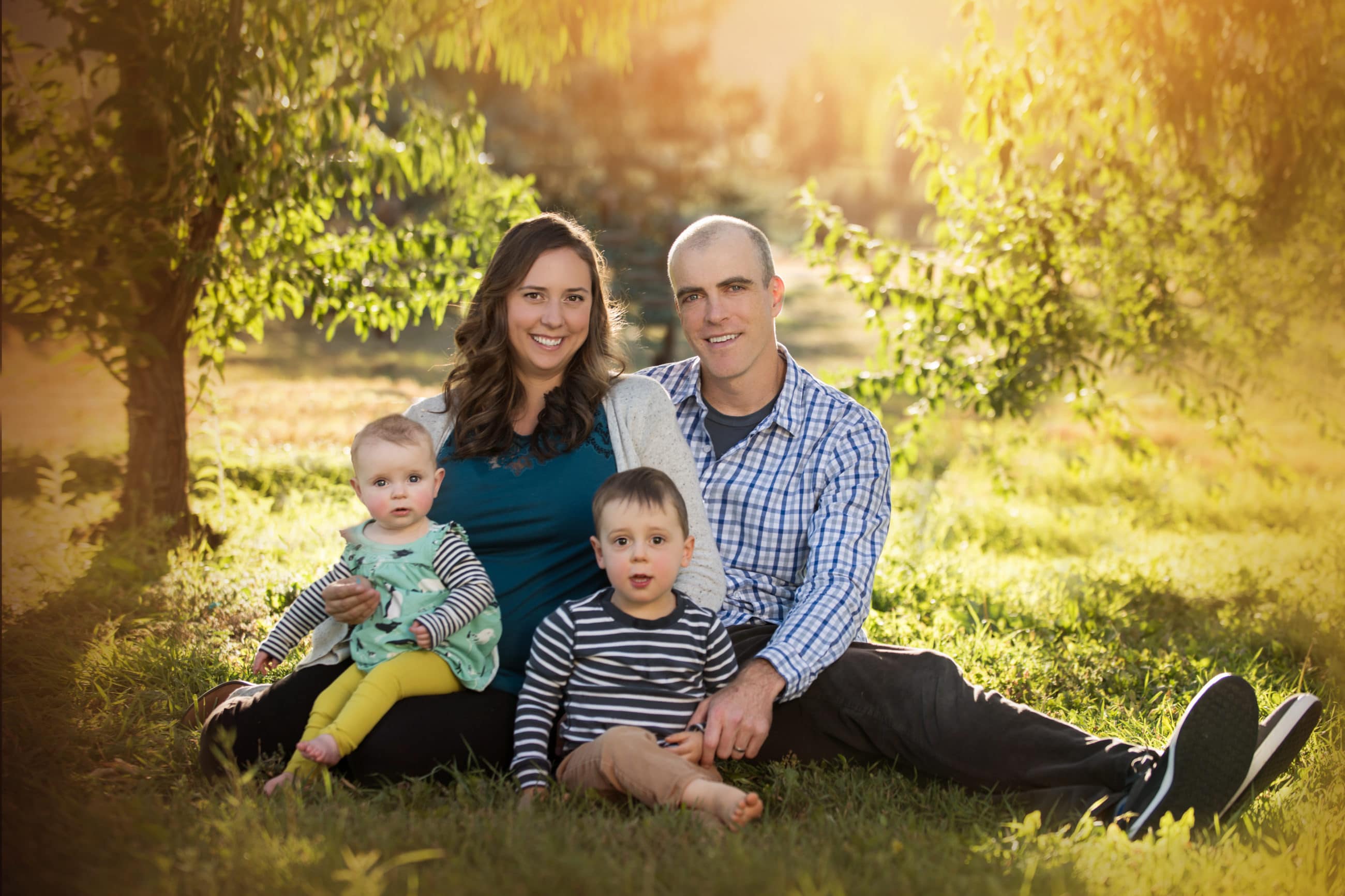 family of four sitting close together in light at sunset - boulder family photographer