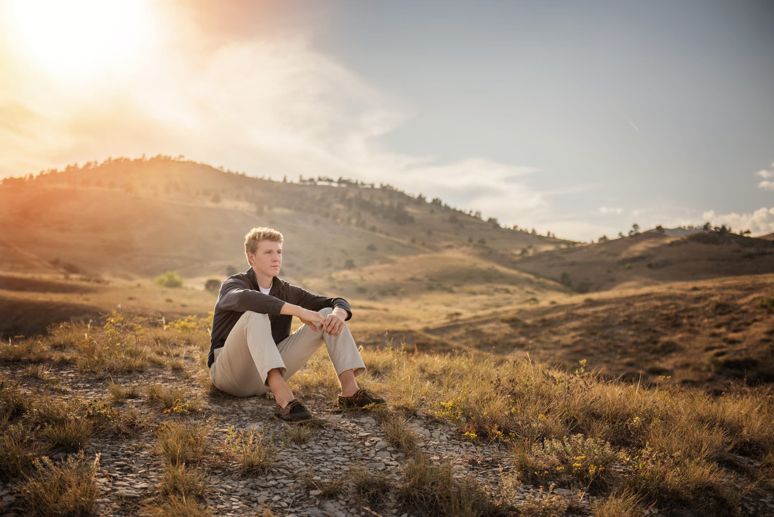 senior guy sitting on mountain top at sunset - boulder senior photographer