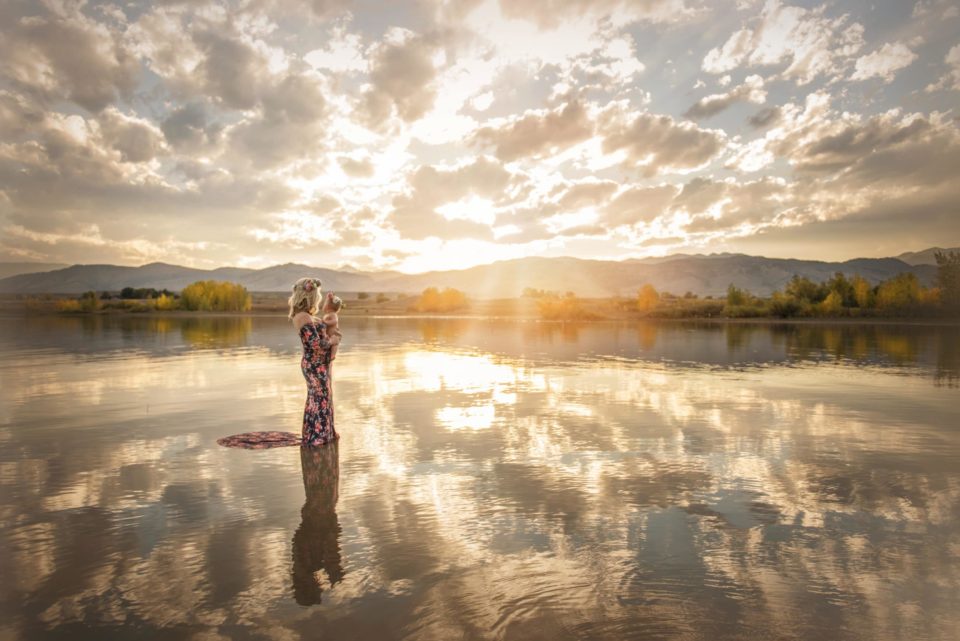 mother holding her baby girl standing in water at sunset - boulder photographer