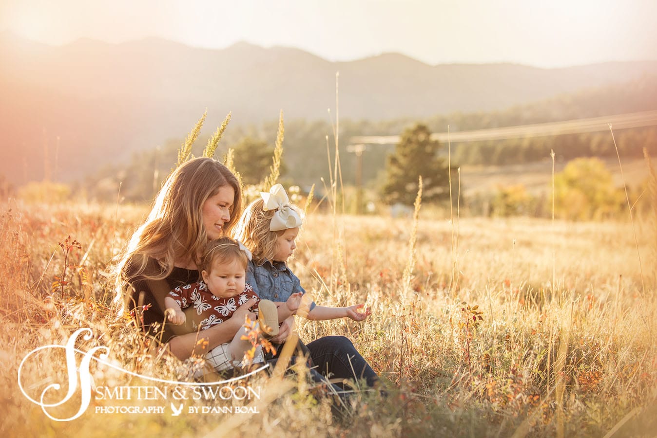 mom holding her two daughters in a field at sunset - boulder photographer