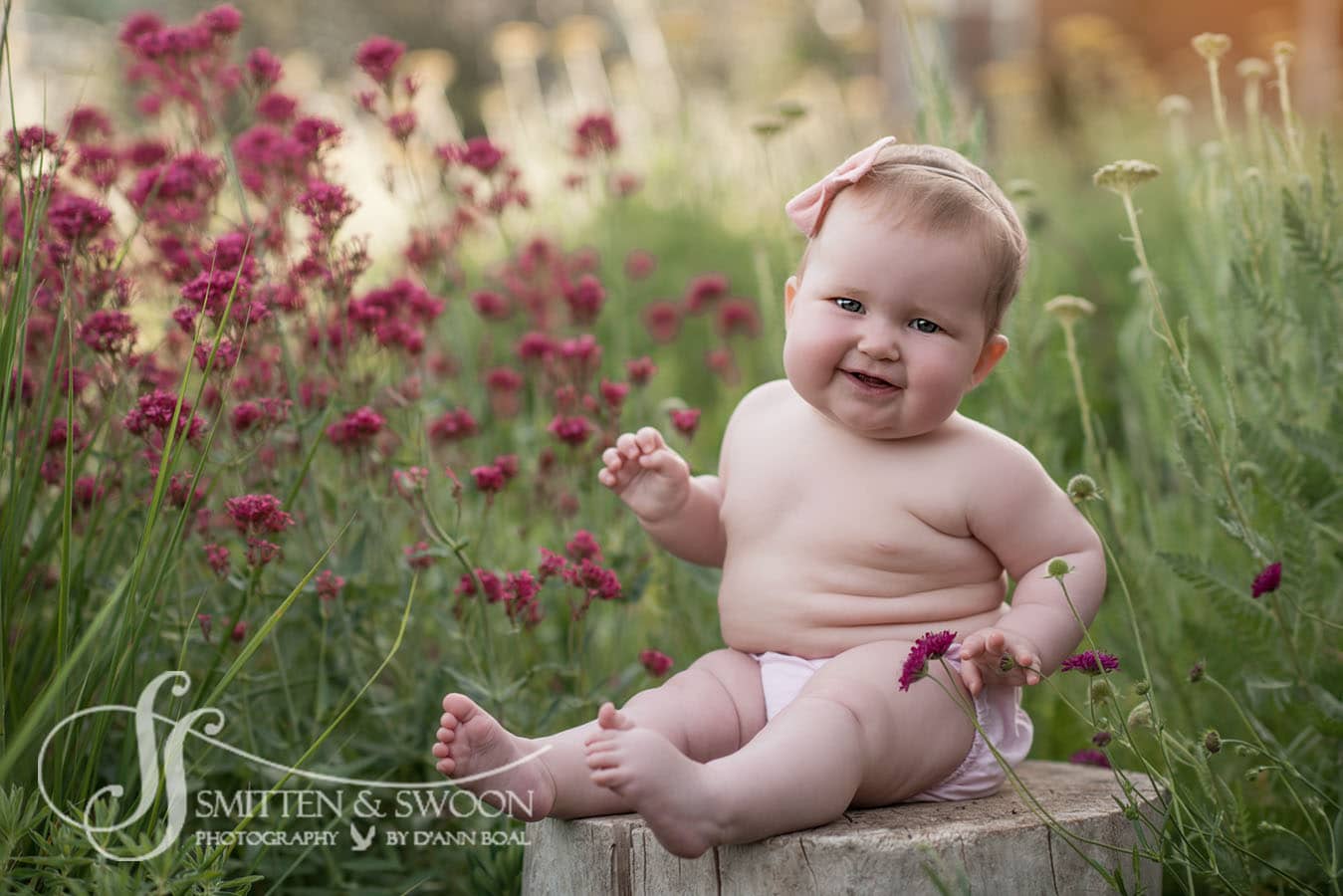 six month baby girl sitting on a tree stump in garden - boulder baby photographer
