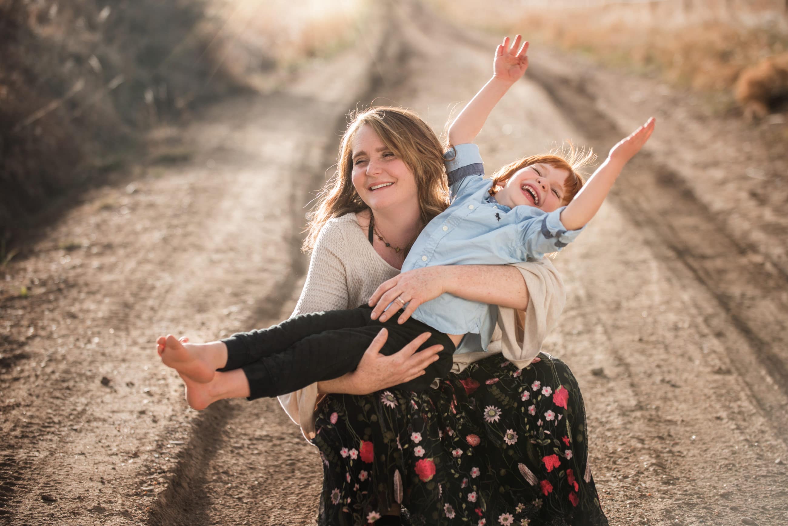 mom and son on dirt road smiling with joy hands in the air - child photography boulder