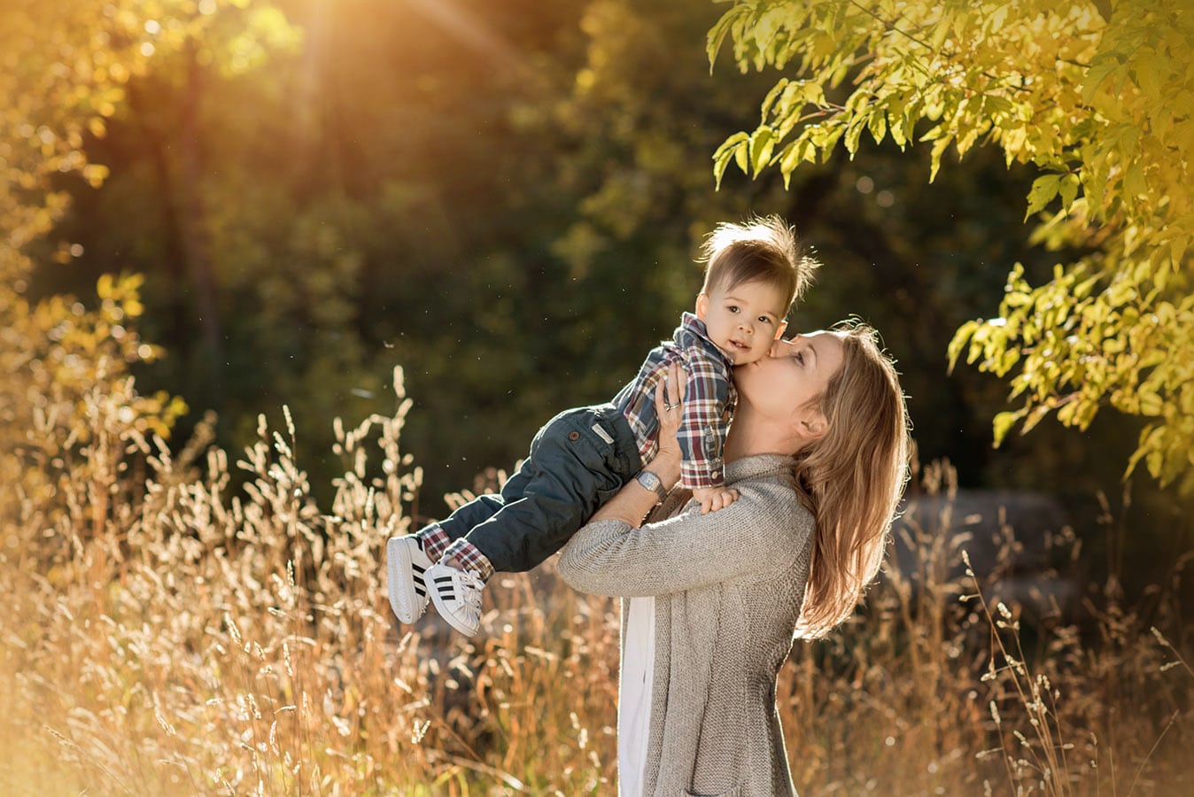 mother holding her baby boy up and kissing him under a yellow tree - boulder's best photographer
