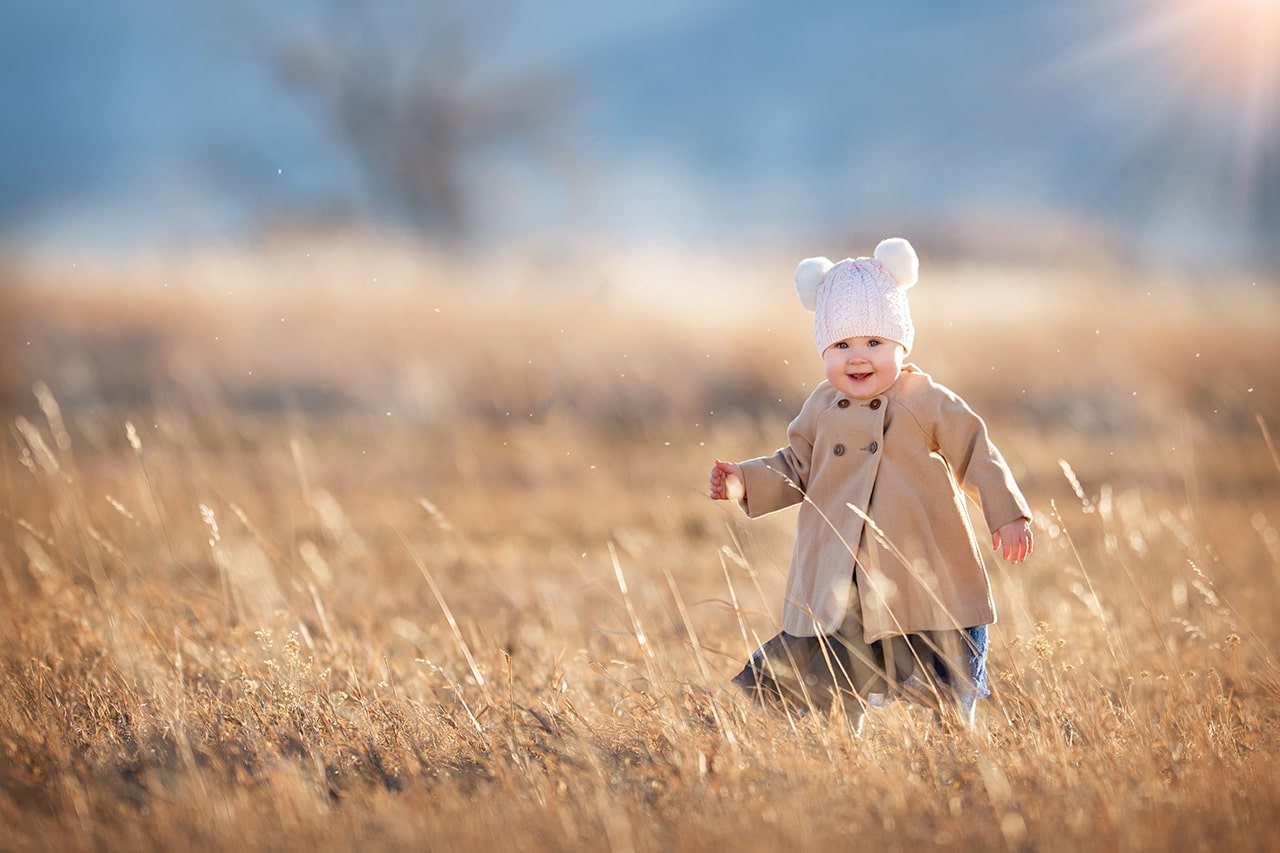 little girl smiling in golden field with sun flare (boulder photographer)