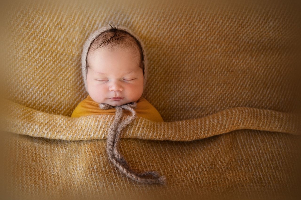 newborn baby boy sleeping with bonnet in yellow blanket (boulder photographer)