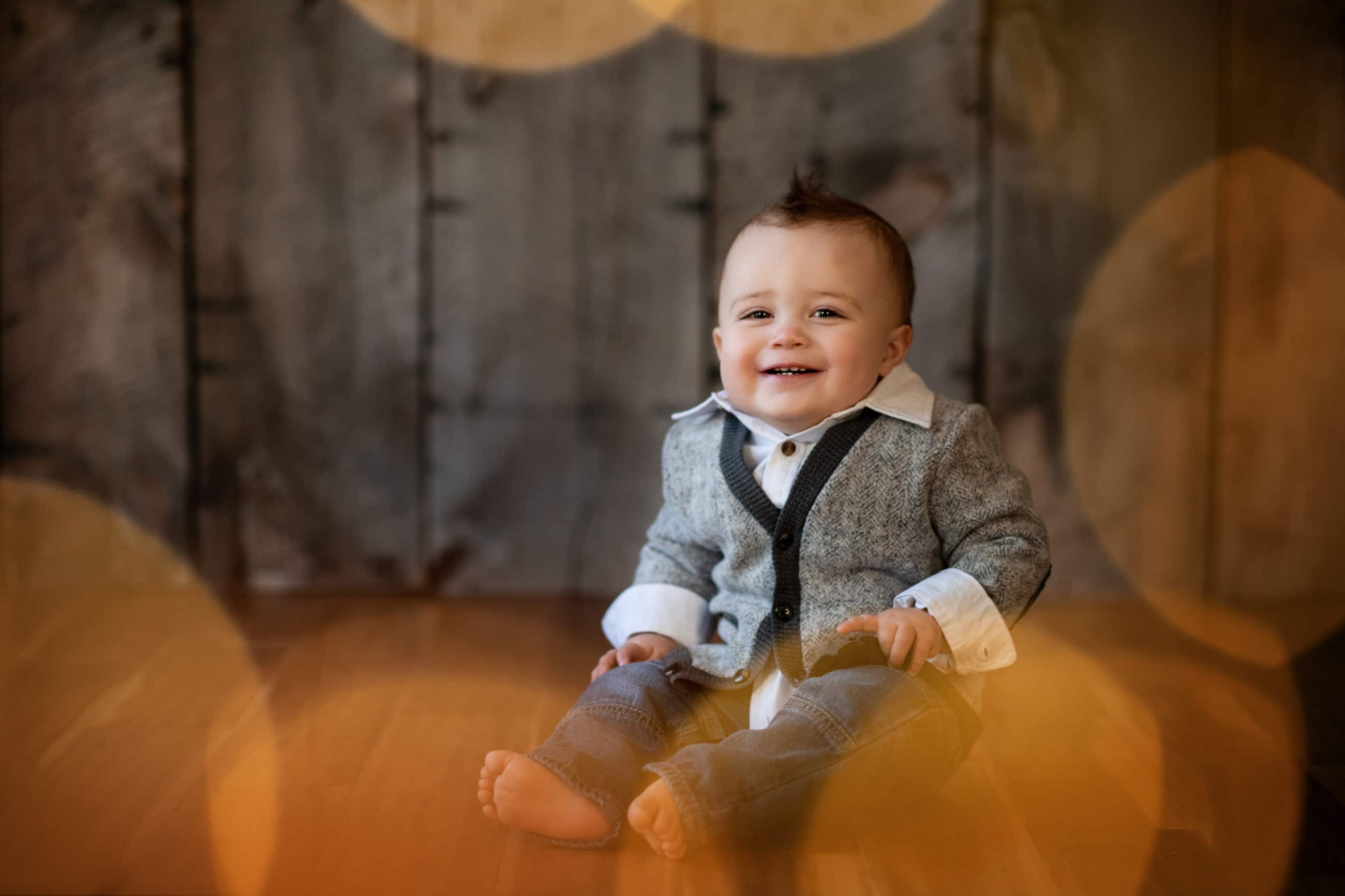 one year old boy with sweater and twinkle light bokeh - boulder newborn photographer