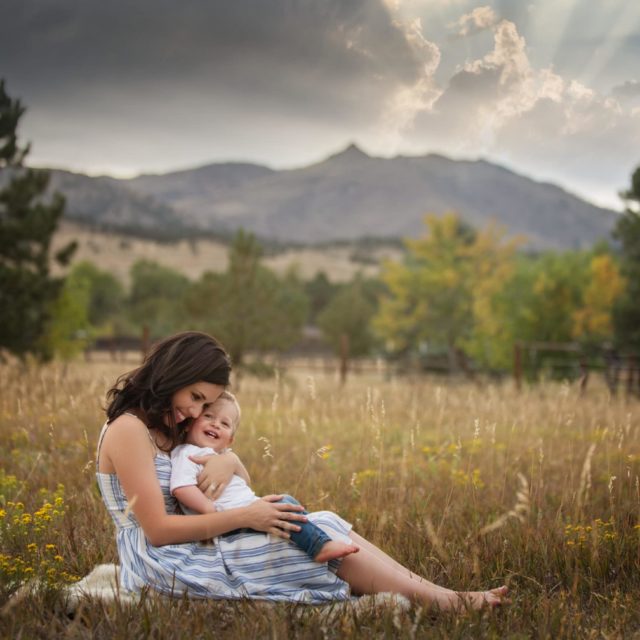 mom and baby boy snuggling in field - boulder family photographer