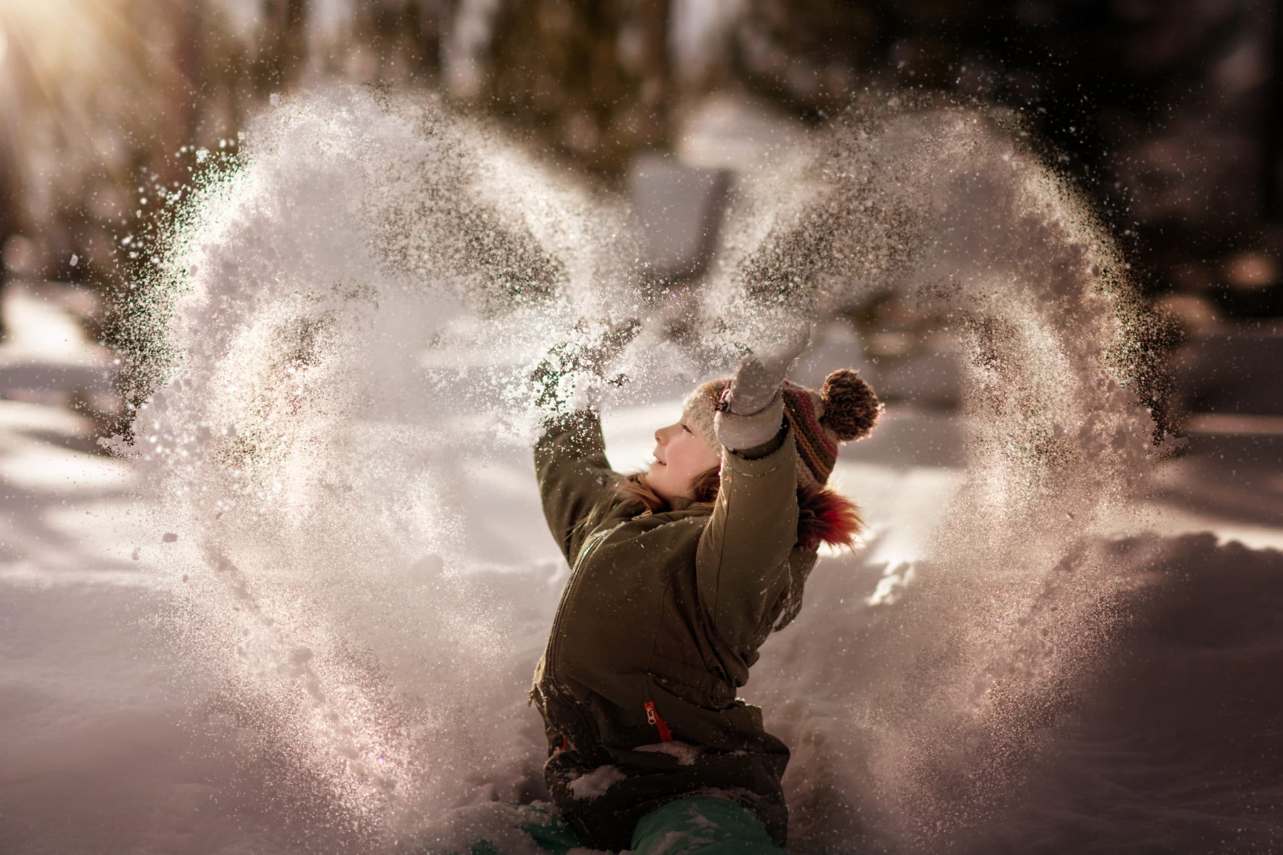girl with green coat throwing snow in the air in the shape of a heart - boulder photographer
