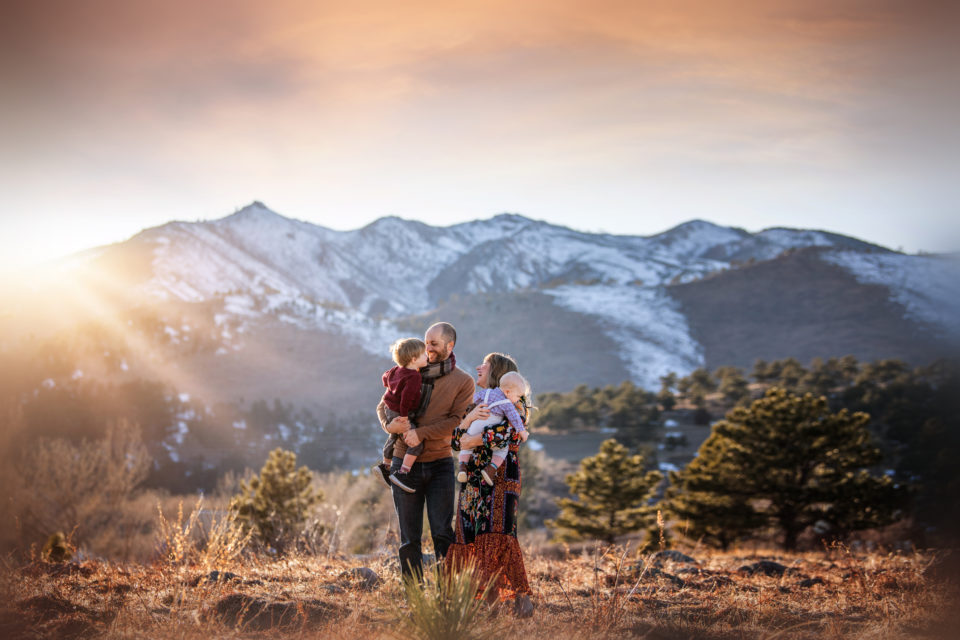 love and light - boulder photographer family of four hugging in field at sunset