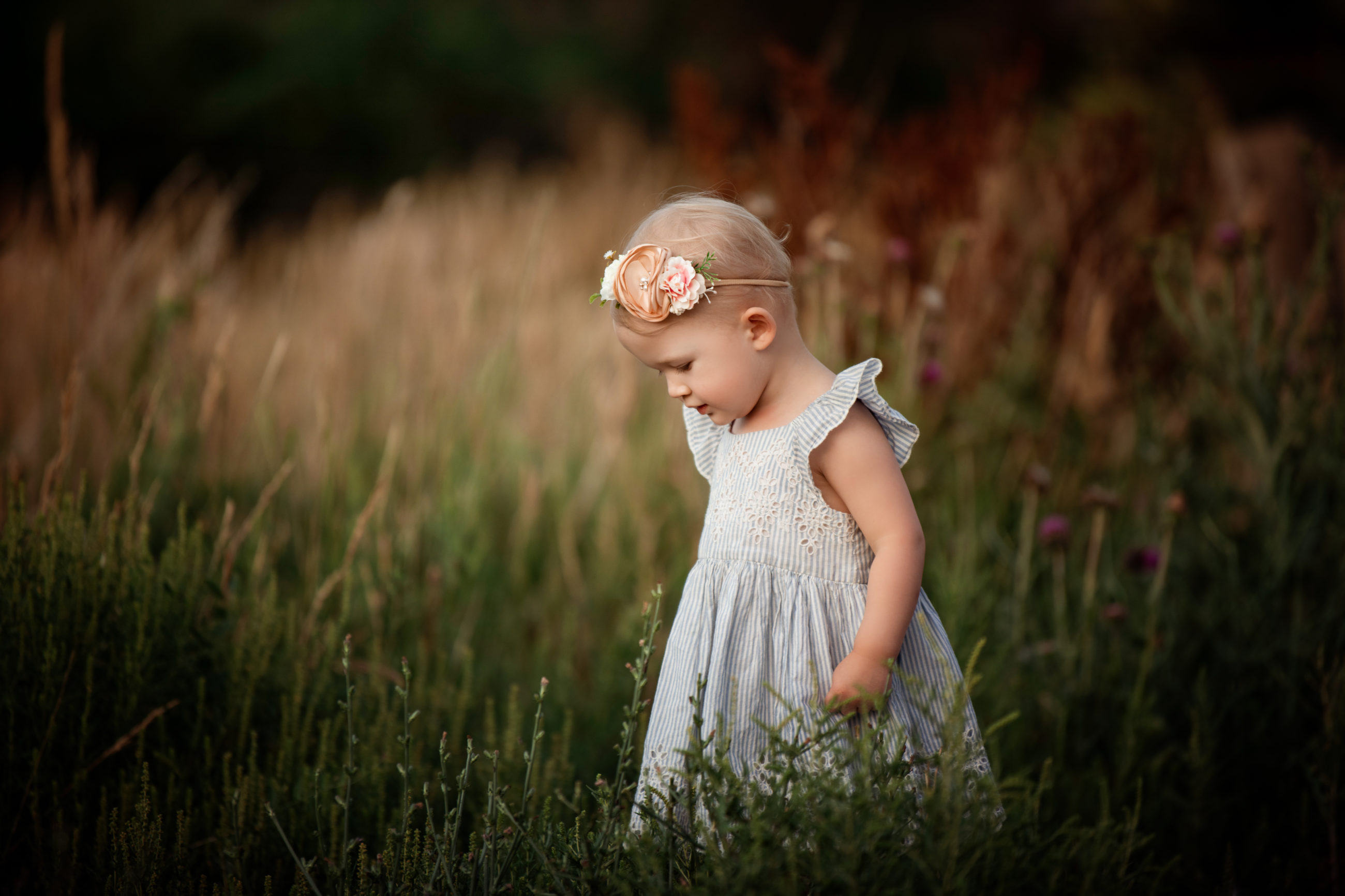 little girl in blue dress with pink flower headband in green field - Mother daughter photo session | boulder family photographer